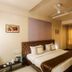 Hotel Bhagyalaxmi in Shirdi guest room with king bed, sitting area, ceiling fan and curtains