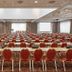 H+ Hotel Wiesbaden Niedernhausen in Niedernhausen meeting room with rows of red banquet chairs and tables