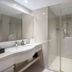Grand Metropark Hotel Hangzhou bathroom with glass shower, vanity sink, and large mirror in Hangzhou