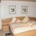 Jaegerstube in Görgeshausen guest room with wooden bed, striped bedding, and framed wall art