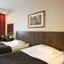 Hotelli Emilia, Hämeenlinna: twin room with two single beds, armchair, and red patterned curtains