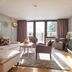 Hotel Zurserhof in Zürs living area with sofa, chairs, TV, and large windows to snowy views