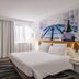 Novotel Paris Créteil Le Lac room with large bed, desk, striped rug and city-themed wall art in Créteil