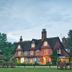Ravenwood Hall Hotel in Bury St. Edmunds, red-brick country house with lit windows and lawn at dusk