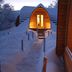 Snow Resort Kirkenes in Kirkenes, snow-covered cabins with lit windows and snowy walkway at dusk