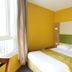 Hôtel de France Boulogne-Billancourt room with double bed, yellow walls and window beside the bed