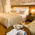 Judita Palace Heritage Hotel in Split: elegant bedroom with stone wall, king bed, and seating area
