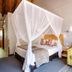 The Cavern in Bonjaneni: cozy bedroom with canopy bed, floral pillows, and patterned sofa