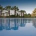 Poolside view at Apartamentos Vista Real in La Línea de la Concepción with palm trees and building reflections