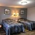 Coastal Inn Kingfisher in Digby: guest room with two double beds, table lamp, and framed wall art