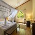 Diamonds Malindi bedroom with canopy bed, mosquito net, bench, and tropical garden view in Malindi