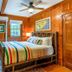 The Lodge on Lake Lure in Lake Lure: cozy wood-paneled bedroom with striped bedding and ceiling fan