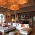 Le Jardin Des Douars in Essaouira features a stylish lounge with curved sofa, coffee table and woven pendant lights.