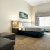 Hilton Garden Inn Riverhead guest room with king bed, desk, armchair and window with curtains