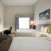 Hilton Garden Inn Riverhead guest room with two beds, desk, TV and window with curtains