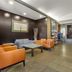Best Western Plus St. Albert lobby seating area with orange chairs, table, and stone accent wall