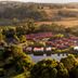 Tall Timbers Tasmania in Smithton, aerial view of lodge cabins beside a pond and rolling countryside