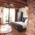 Hazienda Apartmenthotel Gernsbach room with bed, balcony doors, leather chair and brick fireplace