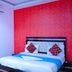 Hotel Ashoka Palace Near Igi Airport, New Delhi guest room with bed, red accent wall and wall-mounted AC