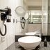 Motel One München-Westend bathroom with vessel sink, mirror, shower and hair dryer in Munich