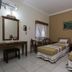 Hotel Mataram Malioboro Yogyakarta room with two twin beds, desk, chair, mirror and tiled floor in Yogyakarta