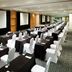 Meeting room at Real Inn Perinorte in Tlalnepantla with rows of tables, white chairs and projection screens.