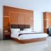 Grand Daira Hotel Palembang in Palembang features a king bed, wood-paneled wall, desk and lounge chair.