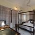 Hotel Harasar Haveli in Bikaner: four-poster bed in a bright guest room with tiled floor and curtains