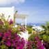 Meli Meli in Thera with white buildings, bougainvillea, palm trees and distant sea view