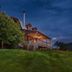 Engadine Inn and Cabins in Candler: rustic cabin with lit porch on a grassy hillside at dusk