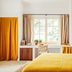 Le Moulin, Lourmarin room with mustard bedspread, window seat and golden curtains