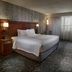 Courtyard by Marriott Fayetteville guest room with king bed, TV, dresser and window with sheer curtains