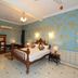 Hotel Harasar Haveli in Bikaner bedroom with carved wooden bed, blue ornate walls, and tiled floor