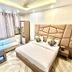 Amrit Villa, New Delhi bedroom with large bed, sofa, coffee table and patterned headboard