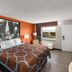 Super 8 by Wyndham Bulls Gap Greeneville Area room with orange accent wall, king bed, and window seat