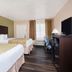Baymont Inn & Suites Lake City guest room with two beds, desk, TV and window seating area