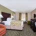 Baymont Inn & Suites Lake City guest room with bed, armchair, desk, TV, and window seating