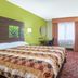 Super 8 by Wyndham Portales guest room with king bed, TV, desk, window air conditioner and patterned carpet