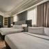 Vibe Hotel Singapore Orchard guest room with two beds, wood flooring, large windows and desk in Singapore