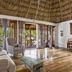 Portofino Beach Resort in San Pedro Town interior with thatched ceiling, sofa, wicker chair and glass coffee table