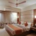Hotel Centra-Ahmedabad room with a king bed, ceiling fan, seating area, and wall-mounted TV in Ahmedabad