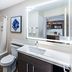 Candlewood Suites Topeka West bathroom with tub shower, vanity, and illuminated mirror in Topeka