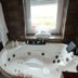 Le Beauséjour in Tregastel: spa bathtub beside a window with bathrobes hanging on the wall
