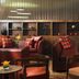 Lingfield Park Marriott Hotel & Country Club lounge with leather seating, tables, and wall-mounted TV in Lingfield