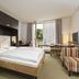 City Hotel Dresden Radebeul guest room with bed, desk, striped chairs and balcony view in Radebeul