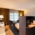 Hotel Mooirivier in Dalfsen guest room with bed, armchair, desk, and room divider