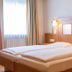Gasthof zum Löwen in Weißenhorn: cozy twin bed room with wood-paneled headboard and window light