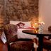 Rumi Wasi in Cusco: cozy room with stone wall, bed, round table, and patterned chairs