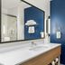 Spark by Hilton Missouri City Sugar Land bathroom with white vanity, mirror, blue accent wall and towel rack