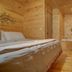 Paradise Hills, Winery Resort & Spa in Blairsville: wood-paneled guest room with bed and small bench